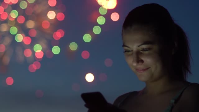 Eine-Mädchen-nutzt-eine-Smartphone-während-ein-Feuerwerk.-Slow-motion