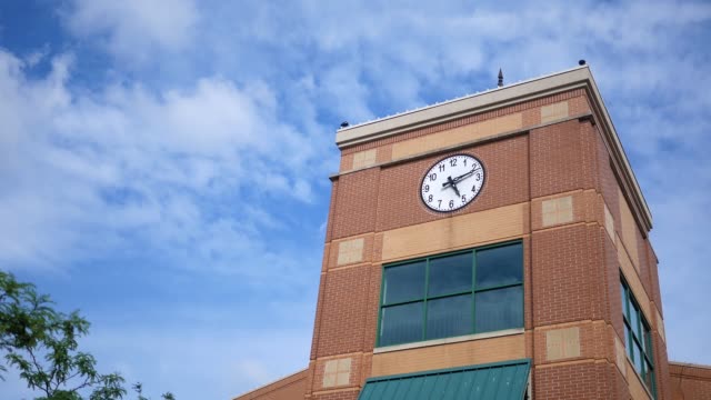 Time-lapse-of-a-clock-tower-modern-building-on-bright-afternoon
