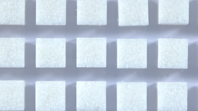 Mesa-Tiro-cubitos-de-grupo-de-azúcar-varían-de-posición-en-fondo-azul-claro