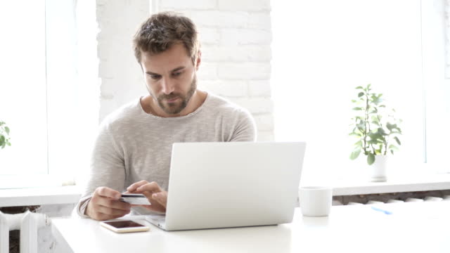 Online-Shopping-with-Bank-Card-by-Handsome-Man-on-Laptop