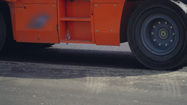 orange-steamroller-for-asphalt-with-four-wheels-stands-on-the-road-at-day