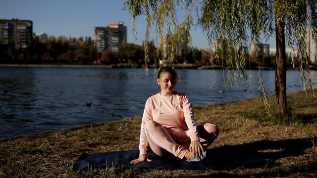 Mädchen-im-Sport-Anzug-auf-einem-Fluss-Yoga-auf-dem-Hintergrund-der-Stadtlandschaft.