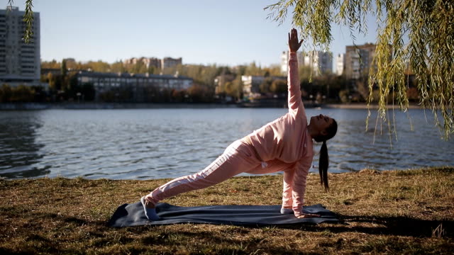 Yoga-en-el-paseo-de-la-metrópolis-moderna.-Chica-en-un-juego-de-los-deportes-en-un-yoga-de-río-en-la-estera.