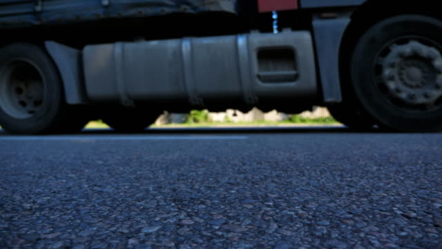 Truck-is-driving-along-an-asphalt-road.-Blurred-car-is-riding-at-the-highway-at-the-sunny-summer-day.-Low-angle-view-Close-up-Slow-motion