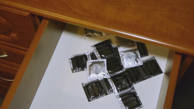 Ein-Mann-nimmt-ein-Kondom-aus-dem-Nachttisch.-Schutz-vor-Aids-und-Schwangerschaft.