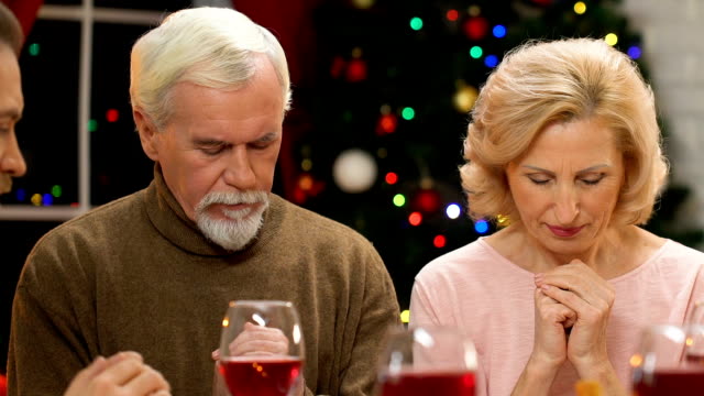 Extended-family-praying-before-Christmas-meal,-dinner-blessing,-holiday-spirit