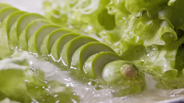 In-Scheiben-geschnittene-Zucchini-fallen-in-den-nassen-Tisch.-Slow-Motion-240-fps