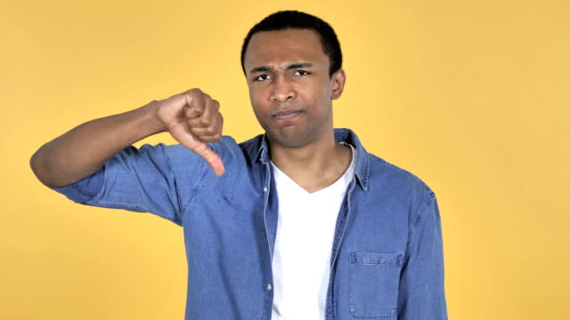 Young-African-Man-Gesturing-Thumbs-Down-Isolated-on-Yellow-Background