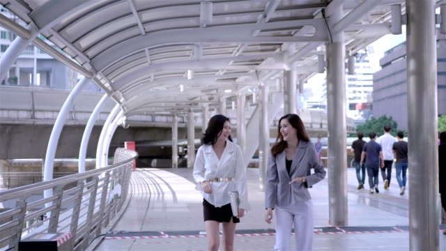 Female-Business-People-Walk-and-Discuss-Business-and-smiling-happily-in-city-centre-Thailand.-SLOW-MOTION