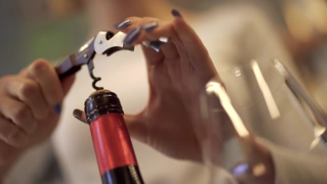 Close-up-of-female-hands-uncorking-a-bottle-of-wine.-Girl-uncorking-the-wine-with-a-corkscrew.
