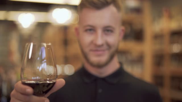 Portrait-of-handsome-man-raising-his-wine-glass-closeup.-The-focus-moves-from-the-wine-glass-to-the-guy-and-back.