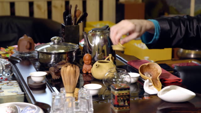 Chinesische-Traditionen.-Master-schüttet-Tee-aus-einer-Glas-Teekanne