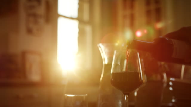 Man-gießt-Rotwein-in-Glas-am-Küchentisch