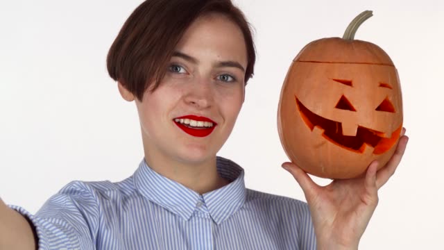 Schöne-rote-Lippen-Frau-macht-Selfies-mit-geschnitzten-Halloween-Kürbis