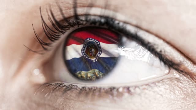 Woman-green-eye-in-close-up-with-the-flag-of-Missouri-state-in-iris,-united-states-of-america-with-wind-motion.-video-concept