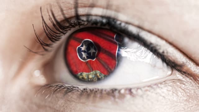 Woman-green-eye-in-close-up-with-the-flag-of-Tennessee-state-in-iris,-united-states-of-america-with-wind-motion.-video-concept