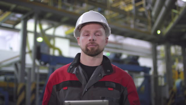 Stolzer-männlicher-Fabrikbetreiber-posiert-vor-der-automatisierten-Produktionslinie
