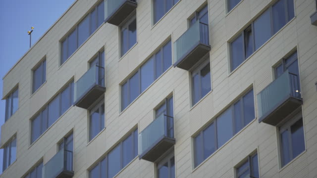 Foto-de-cerca-del-moderno-edificio-residencial.-Edificio-residencial-exterior-con-fondo-celeste-azul.-El-edificio-cuenta-con-exterior-con-pequeños-balcones