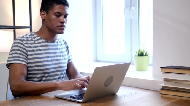 Joven-negro-hombre-malestar-por-la-pérdida,-trabajar-en-ordenador-portátil