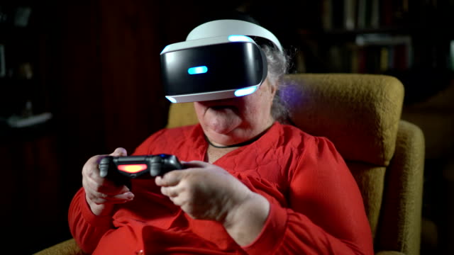 Elderly-woman-in-front-of-TV-screen-uses-VR-headset-and-wireless-gaming-controller