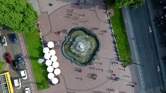 An-aerial-shot-of-a-fountain-on-an-avenue-along-which-people-walk