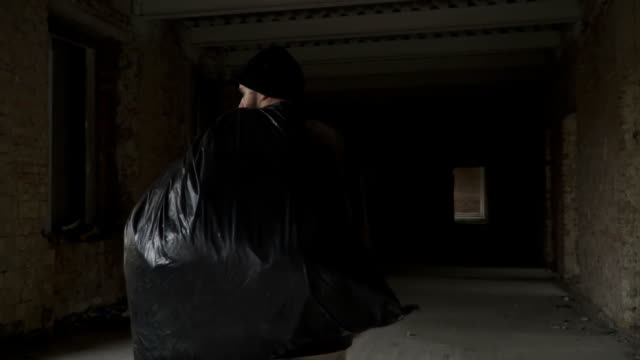 Dirty-homeless-with-garbage-bag-walks-in-abandoned-building