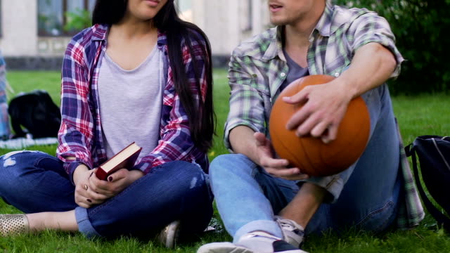 Mädchen-mit-Buch,-Kerl-mit-Basketball-Ball-Rasen-sitzen-und-reden,-Beziehung
