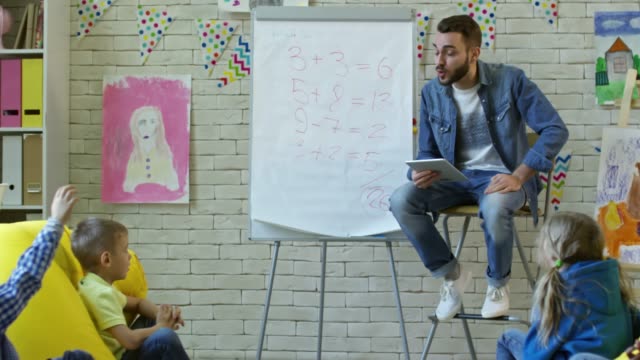 Junger-Mann-Kinder-lehren-in-komfortable-Klassenzimmer