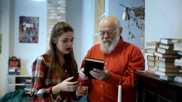 Grandfather-and-granddaughter-discusses-book-standing-near-the-the-piano