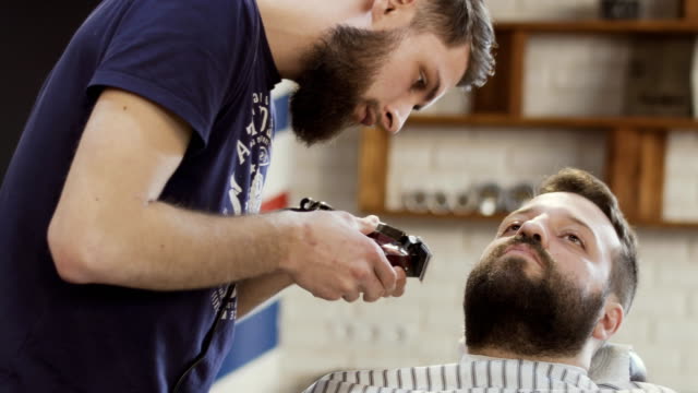Estilista-hace-estilo-de-barba-con-máquina-de-afeitar-eléctrica