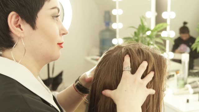 Weibliche-Friseur-machen-Massage-Kopf-junge-Frau-im-Friseursalon.-Haircutter-arbeiten-mit-Klienten-im-Beauty-Salon-hautnah