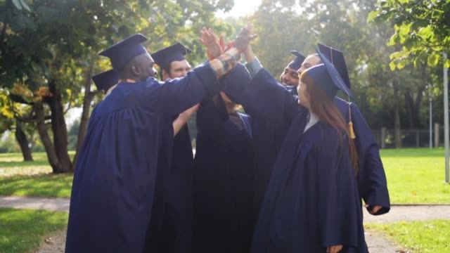 happy-students-in-mortar-boards-making-high-five