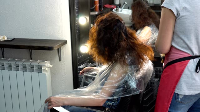 Haar-Obacht.-Frau-Friseur-Pinsel-malt-die-Haare-des-Mädchens-in-einem-Schönheitssalon.