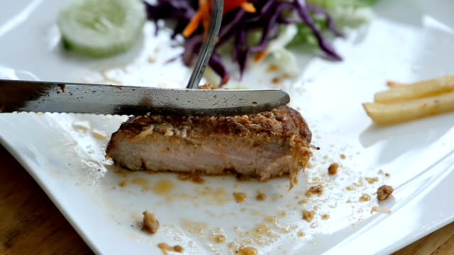Slow-Motion-Hand-of-woman-holding-in-fork-and-knife-cuts-the-steak