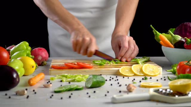 Chef-is-cutting-vegetables-in-the-kitchen,-slicing-green-bell-pepper