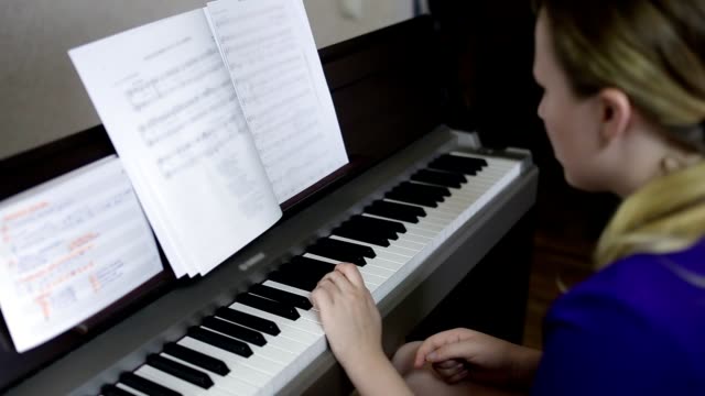 Teen-girl-plays-on-the-keyboard-of-the-digital-piano.