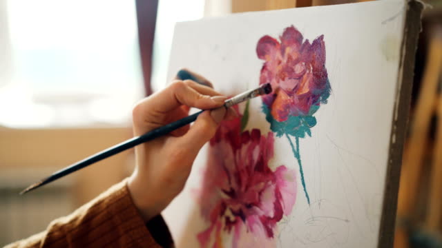 Close-shot-of-dirty-girl's-hand-holding-brush-and-painting-flowers-beautiful-still-life-picture-working-in-workshop-alone.-Creativity-and-art-concept.