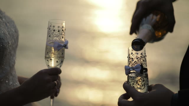 Champagner-wird-in-ein-Glas-Hochzeit-auf-dem-Hintergrund-des-Meeres-aus-Bottel-gegossen.-Schönen-Bräutigam-und-Braut.-Slow-motion