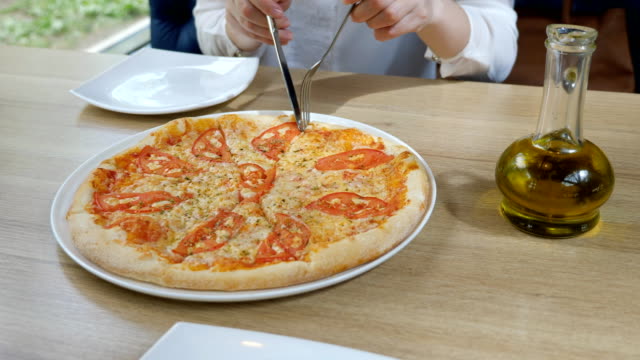 Pizzeria.-Junge-Frau-nimmt-ein-Stück-Pizza-in-ihrem-Teller