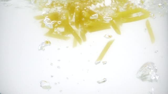 Billige-geschmacklos-Pasta-in-das-schlammige-kochendes-Wasser,-Slow-Motion-auf-weißem-Hintergrund-geworfen,