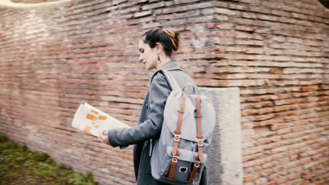 Camera-follows-young-excited-traveler-woman-with-backpack-expolring-ancient-historic-red-brick-ruins-of-Ostia,-Italy.