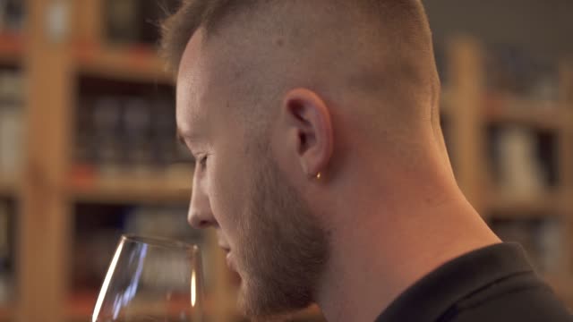 Portrait-of-handsome-male-sniffing-wine-in-the-glass-close-up-in-profile-Man-tastes-alcohol-drink-and-admires-it