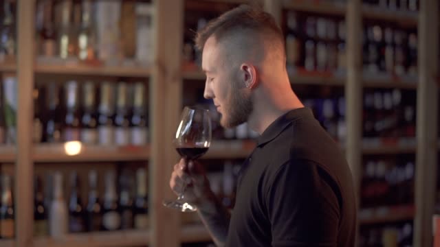 Portrait-of-handsome-male-in-profile-sniffing-wine-in-the-glass.-Man-raise-up-alcohol-drink-glass.-Customer-is-in-alcohol-shop.