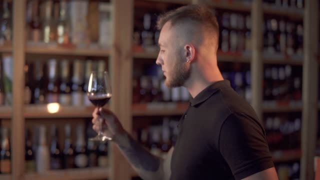 Portrait-of-handsome-male-in-profile-shaking-wine-in-the-glass-Man-admires-alcoholic-drink
