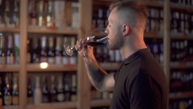 Portrait-of-handsome-male-in-profile-admiring-wine-in-the-glass.-Man-tastes-alcoholic-drink-and-loves-it.-Customer-is-in-alcohol-shop