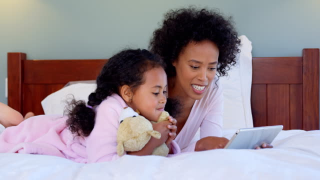 Vista-frontal-de-negro-madre-e-hija-con-tableta-digital-en-cómoda-casa-4k