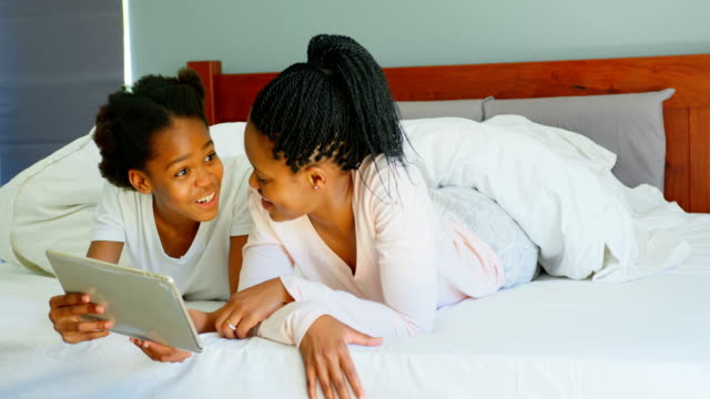 Vorderansicht-der-Mitte-Erwachsenen-schwarzen-Mutter-und-Tochter-mit-digital-Tablette-auf-Bett-im-gemütlichen-Heim-4k