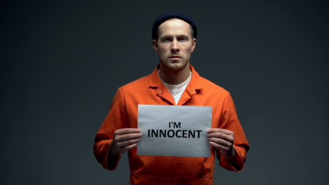 European-imprisoned-male-holding-I-am-innocent-sign-in-cell,-asking-for-justice