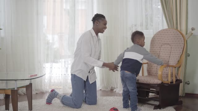 Zuversichtlich-schöne-afrikanische-Amerikanerin,-die-mit-ihrem-kleinen-lustigen-Sohn-spielt
