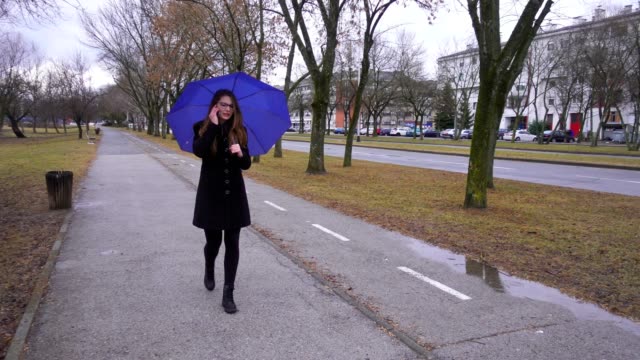 Junge-Frau-mit-Regenschirm-mit-Smartphone